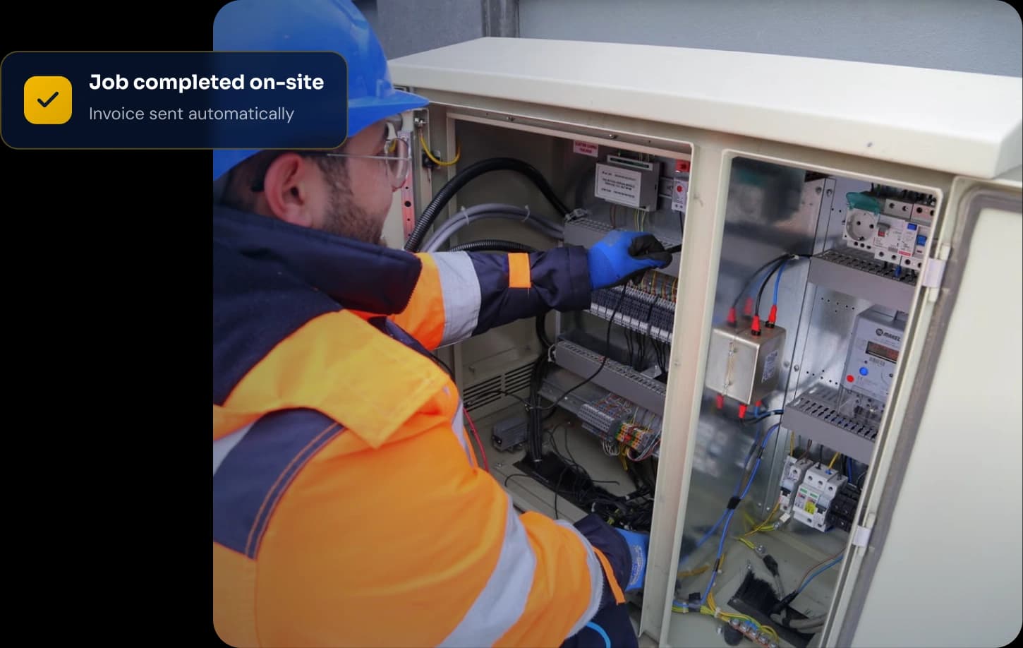 Field technician in a hard hat working on an electrical control panel