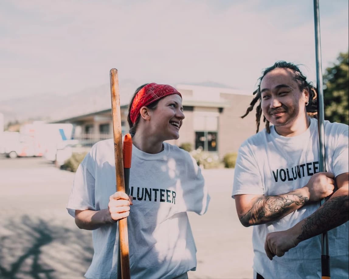 Two volunteers smiling outdoors at a community project